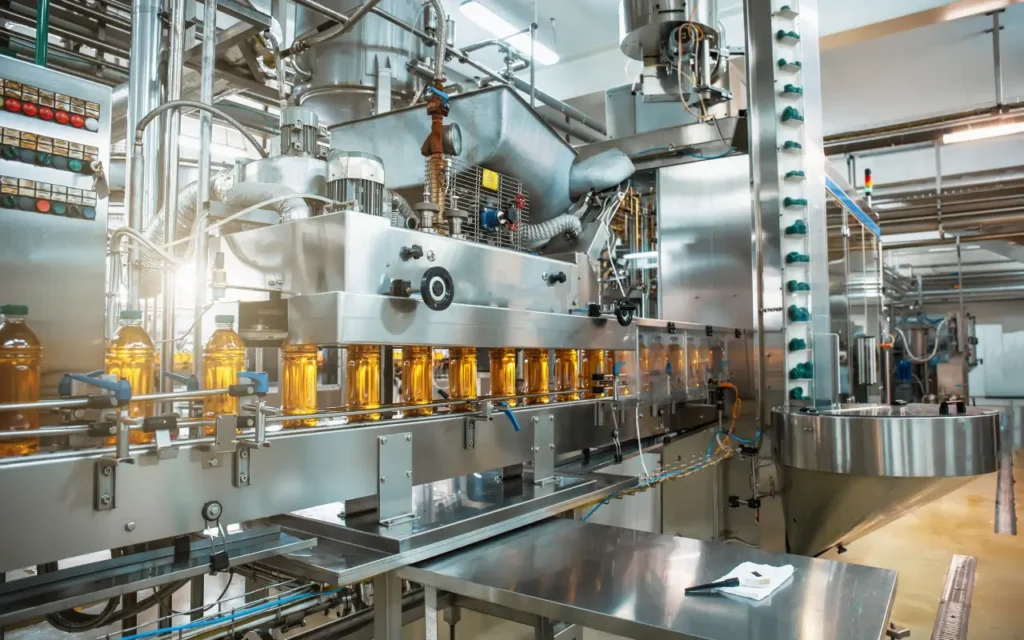 Automated beverage bottling line filling plastic bottles with amber liquid in a stainless-steel food processing plant